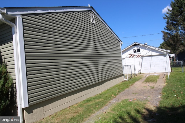 view of side of home with a detached garage, an outbuilding, and fence