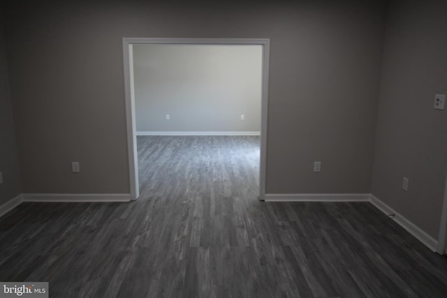 empty room with baseboards and dark wood finished floors