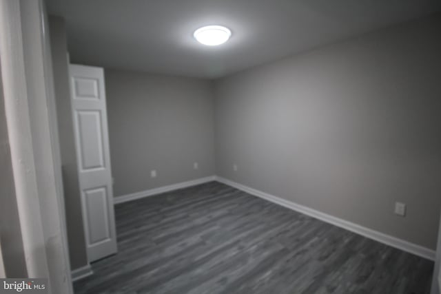 empty room featuring baseboards and dark wood-style floors