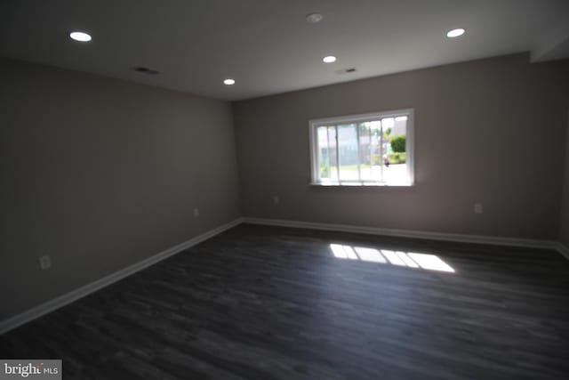 spare room featuring visible vents, recessed lighting, baseboards, and dark wood-style flooring