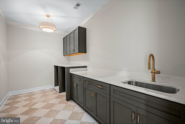 kitchen with light stone countertops, gray cabinetry, and sink