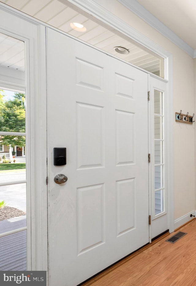 doorway to outside featuring ornamental molding and light hardwood / wood-style flooring