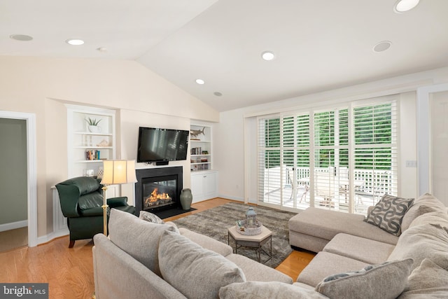 living room with light hardwood / wood-style flooring, built in features, and vaulted ceiling