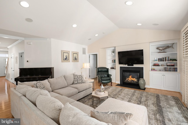 living room featuring lofted ceiling, built in shelves, light hardwood / wood-style flooring, and crown molding