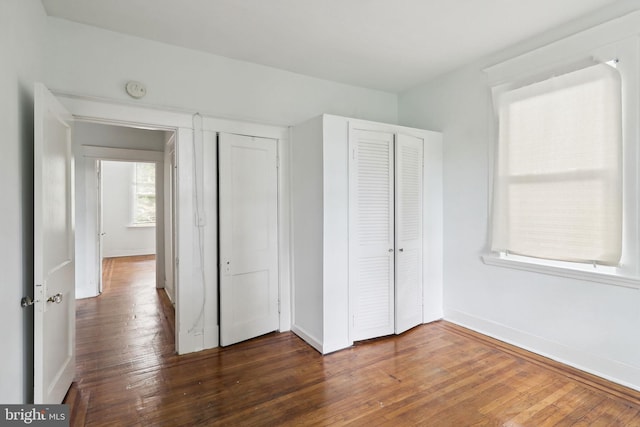 unfurnished bedroom featuring a closet and dark hardwood / wood-style flooring