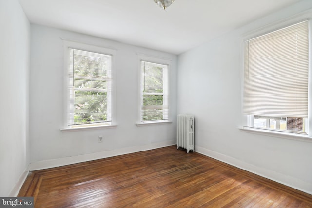 spare room with radiator, a healthy amount of sunlight, and dark hardwood / wood-style flooring