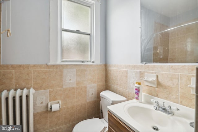 bathroom with tile walls, radiator, vanity, and toilet