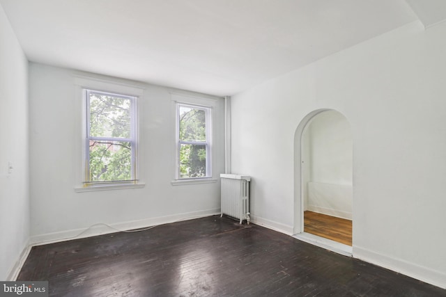 empty room featuring radiator and dark wood-type flooring