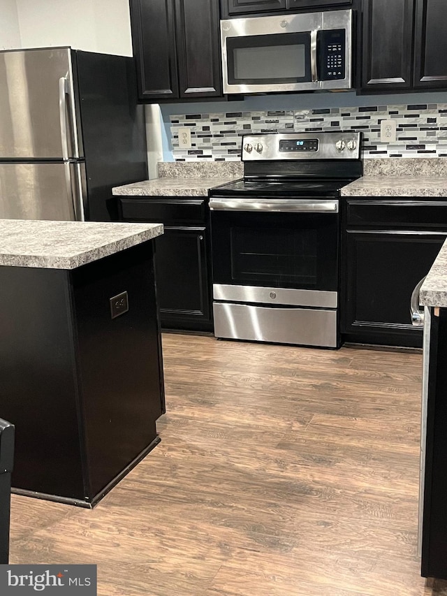 kitchen with appliances with stainless steel finishes, light hardwood / wood-style flooring, and tasteful backsplash