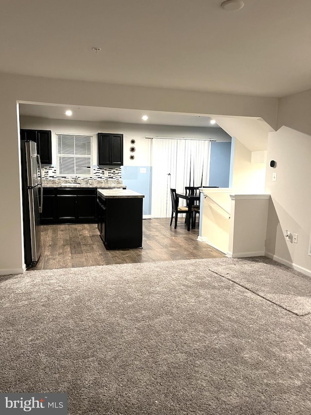 kitchen with tasteful backsplash, stainless steel refrigerator, light wood-type flooring, and a kitchen island