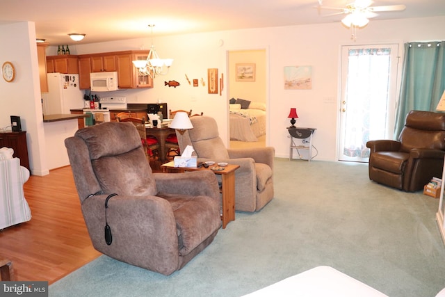 living room with light wood-type flooring and ceiling fan with notable chandelier