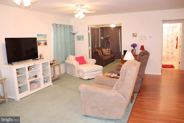 living area with baseboards, ceiling fan, and wood finished floors