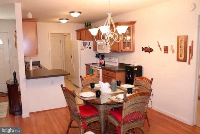 dining area with light wood-type flooring, a chandelier, and sink