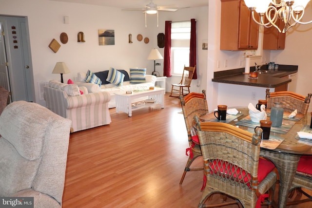 living room with light wood-style floors and ceiling fan with notable chandelier