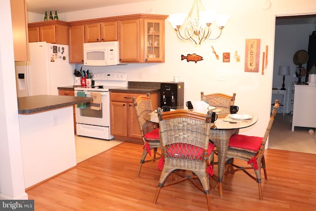 kitchen featuring pendant lighting, white appliances, light hardwood / wood-style flooring, and a notable chandelier