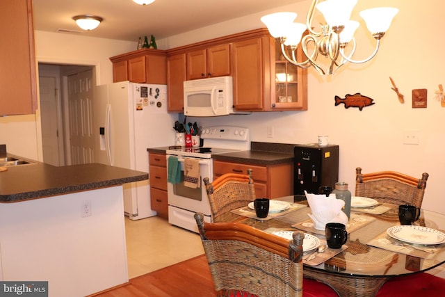 kitchen with decorative light fixtures, white appliances, light hardwood / wood-style floors, sink, and a chandelier