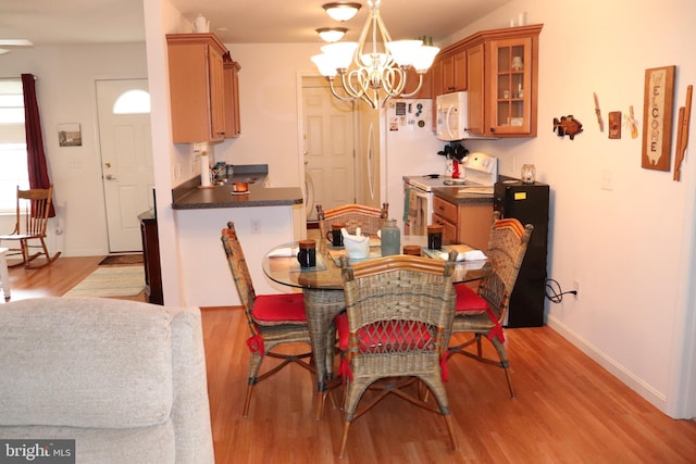 dining room with light wood-type flooring, baseboards, and a chandelier