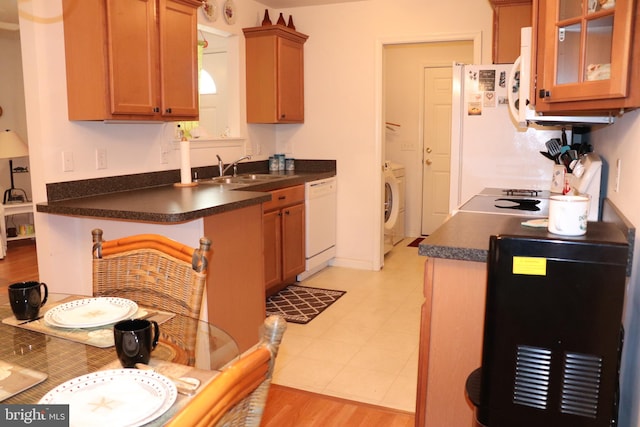 kitchen with light wood-type flooring, white appliances, kitchen peninsula, sink, and washer / clothes dryer