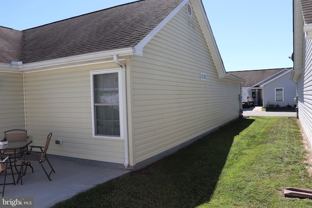 view of home's exterior with a patio area, a lawn, and a shingled roof