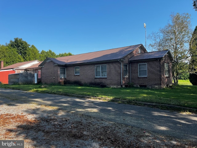 single story home featuring a front yard, brick siding, and metal roof