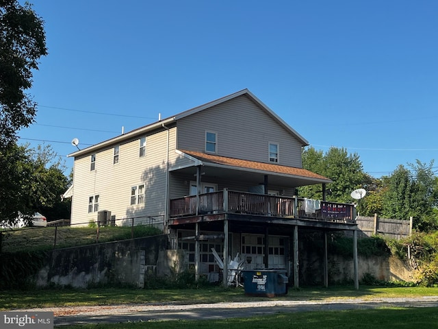 back of property featuring a lawn, a wooden deck, and fence