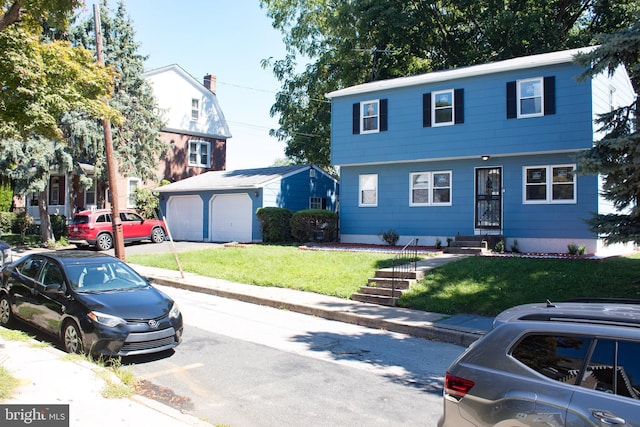 view of front of property with a garage, a front lawn, and an outbuilding