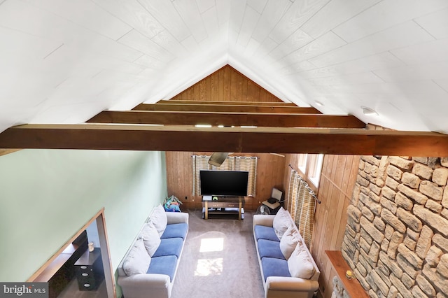 living room featuring lofted ceiling with beams, wood walls, and carpet floors