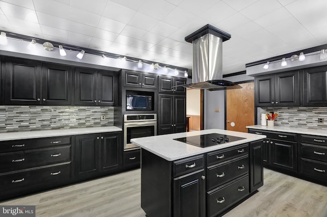 kitchen with backsplash, black appliances, island range hood, a kitchen island, and light hardwood / wood-style floors