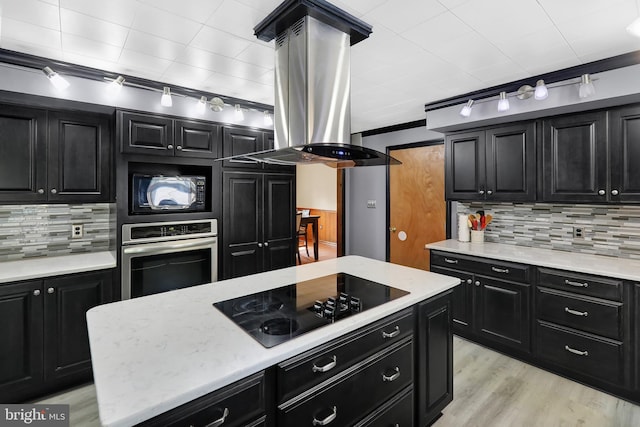 kitchen featuring light wood-type flooring, black appliances, a center island, and island exhaust hood