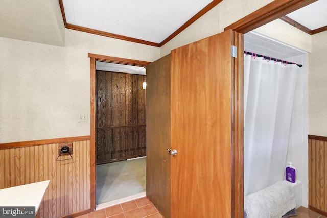 bathroom featuring tile patterned flooring, crown molding, and wood walls