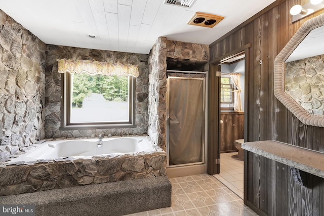 bathroom with shower with separate bathtub, toilet, wood walls, and tile patterned floors