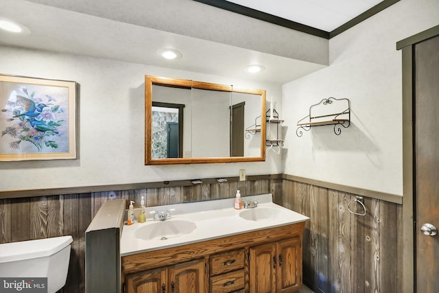 bathroom with ornamental molding, vanity, toilet, and wooden walls