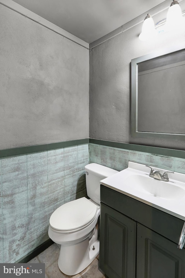 bathroom featuring vanity, toilet, and tile walls