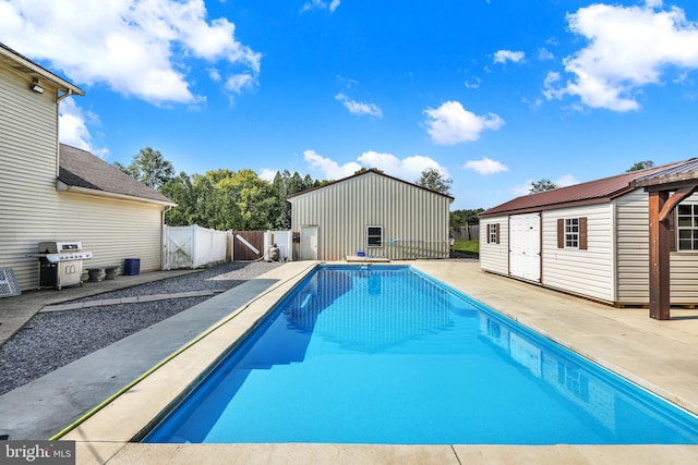 view of pool with grilling area, an outdoor structure, and a patio