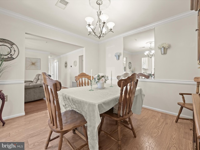 dining space featuring light hardwood / wood-style flooring, crown molding, and a chandelier