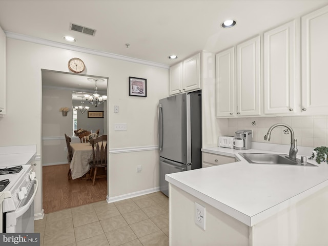 kitchen featuring stainless steel fridge, white stove, sink, white cabinets, and light tile patterned floors