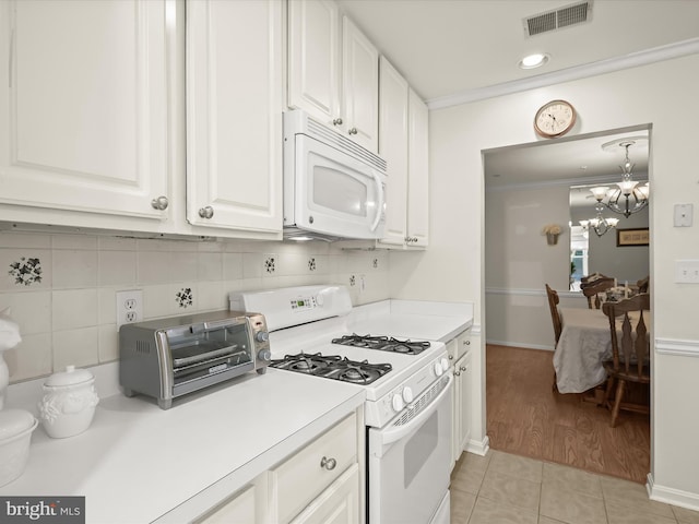 kitchen featuring white cabinets, light tile patterned floors, white appliances, a chandelier, and crown molding