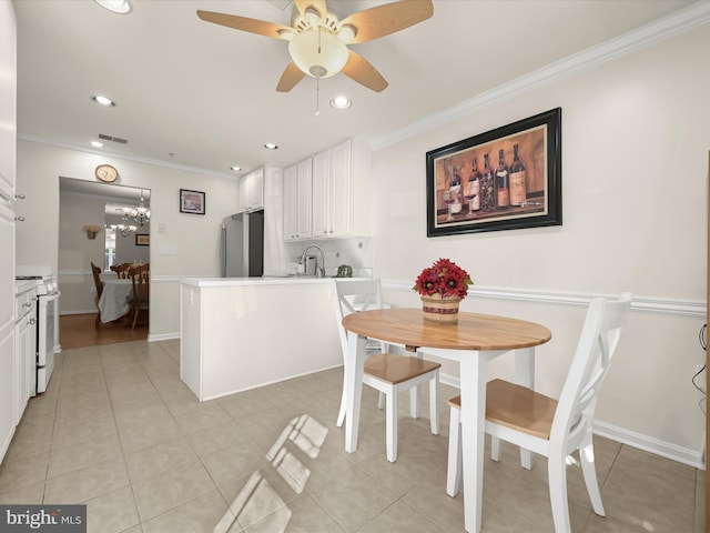 tiled dining area with sink, ceiling fan with notable chandelier, and ornamental molding