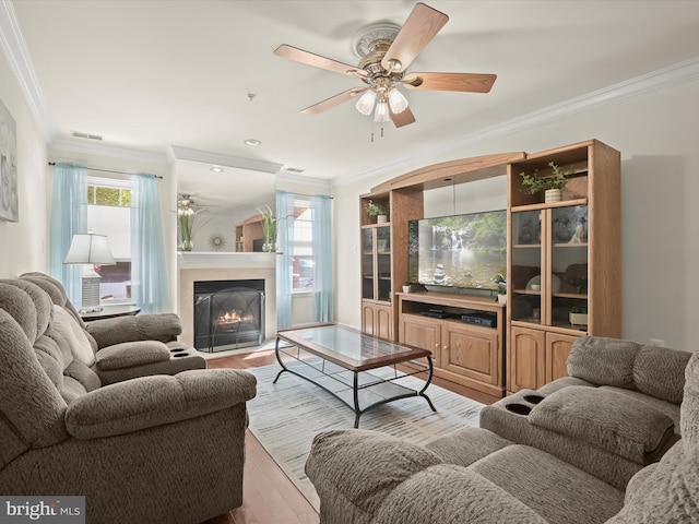 living room with light wood-type flooring, crown molding, and ceiling fan