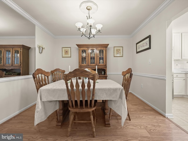 dining area featuring an inviting chandelier, light wood-type flooring, and crown molding