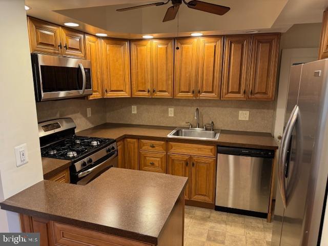 kitchen featuring ceiling fan, appliances with stainless steel finishes, tasteful backsplash, and sink