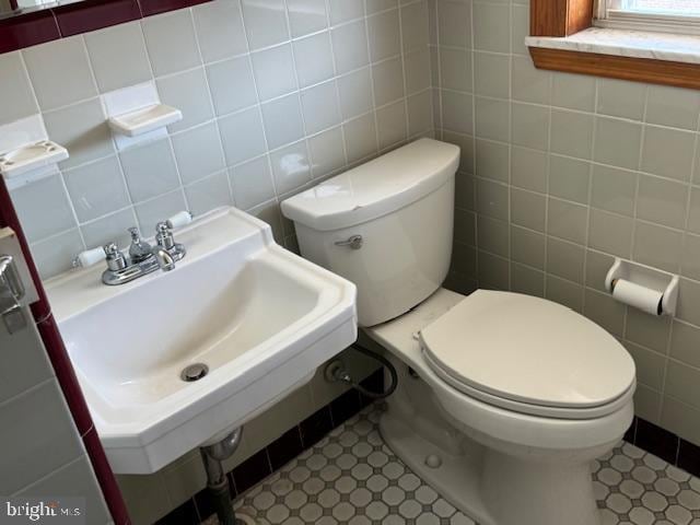 bathroom with tile walls, backsplash, toilet, sink, and tile patterned floors