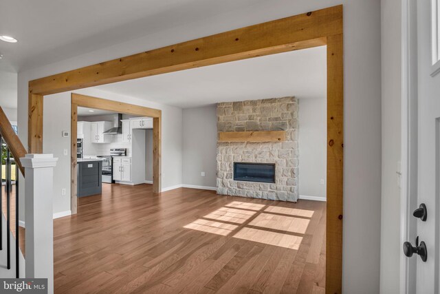 unfurnished living room with stairs, baseboards, wood finished floors, and a fireplace