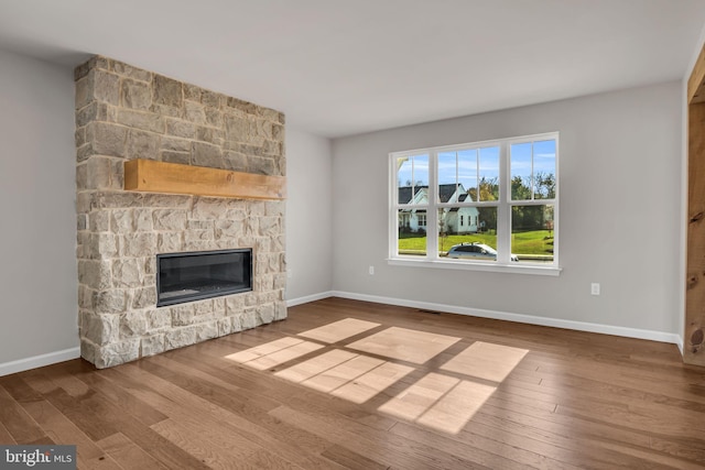 unfurnished living room with a fireplace, baseboards, and wood finished floors