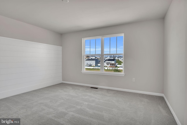 carpeted spare room featuring visible vents and baseboards