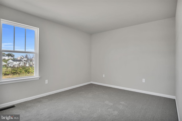 carpeted spare room with visible vents and baseboards