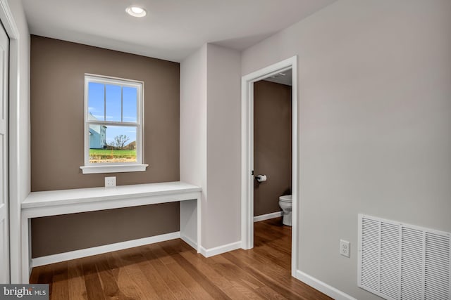 hallway with visible vents, baseboards, and wood finished floors