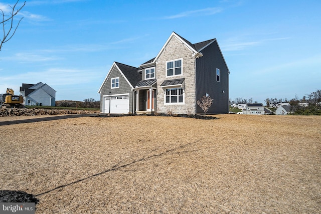 view of front of property featuring stone siding, a garage, metal roof, and a standing seam roof