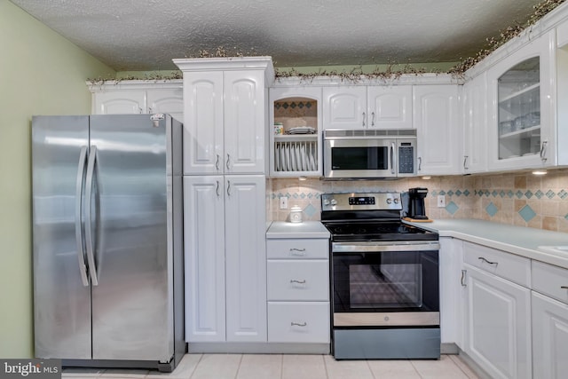 kitchen featuring a textured ceiling, light tile patterned flooring, stainless steel appliances, and white cabinets