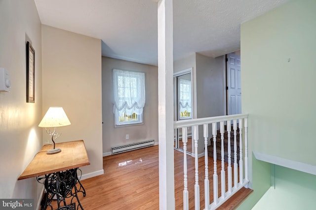 hallway featuring light wood-type flooring, a textured ceiling, and a baseboard radiator